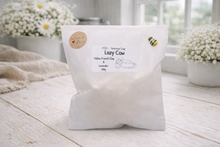 Load image into Gallery viewer, White bag labeled 'Lazy Cow' on a wooden surface with flowers in the background