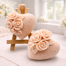 Load image into Gallery viewer, A handmade vegan soap gift set, featuring a central heart-shaped relief surrounded by a border of intricate rose flowers and delicate foliage, displayed on a small wooden easel.