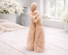 Load image into Gallery viewer, A 3D handmade vegan soap, sculpted as a mother and daughter in a tender standing embrace, featuring an intricate embossed floral and vine pattern on their dresses.