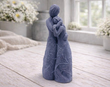 Load image into Gallery viewer, A 3D handmade vegan soap, sculpted as a mother and daughter in a tender standing embrace, featuring an intricate embossed floral and vine pattern on their dresses.