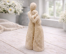 Load image into Gallery viewer, A 3D handmade vegan soap, sculpted as a mother and daughter in a tender standing embrace, featuring an intricate embossed floral and vine pattern on their dresses.