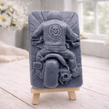 Load image into Gallery viewer, detailed handmade vegan soap gift featuring a motorcycle rider with a skull emblem on their jacket, displayed on a wooden easel against a whimsical farmhouse decor background