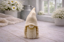 Load image into Gallery viewer, A handmade vegan soap sculpted in the shape of a female gnome (or gonk), featuring a tall, slightly curved hat pulled over the eyes and two thick, textured plaits framing a textured dress, in a natural cream colour.