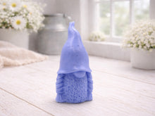 Load image into Gallery viewer, A handmade vegan soap sculpted in the shape of a female gnome (or gonk), featuring a tall, slightly curved hat pulled over the eyes and two thick, textured plaits framing a textured dress, in a natural cream colour.