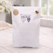 Load image into Gallery viewer, White bag labeled 'Ouija Board' on a wooden surface with a blurred background