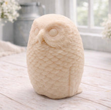 Load image into Gallery viewer, A detailed handmade vegan soap in the shape of an owl with intricate feather textures, displayed on a light wooden table with white flowers in the background.