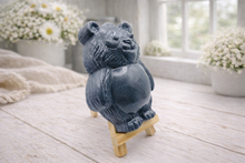 Load image into Gallery viewer, Handmade vegan soap sculpted in the shape of a round, sitting panda bear with detailed fur textures and a friendly expression, displayed on a small wooden easel.