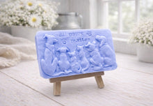 Load image into Gallery viewer, A rectangular handmade vegan soap bar gift, featuring a detailed relief carving of several dogs and a cat sitting together, with the words "all paws matter" and two paw prints embossed at the top, displayed on a wooden easel. Made in Blackpool.