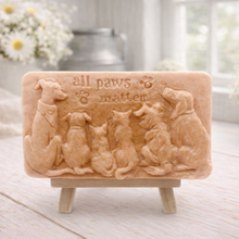 Load image into Gallery viewer, A rectangular handmade vegan soap bar gift, featuring a detailed relief carving of several dogs and a cat sitting together, with the words "all paws matter" and two paw prints embossed at the top, displayed on a wooden easel. Made in Blackpool.