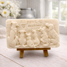 Load image into Gallery viewer, A rectangular handmade vegan soap bar gift, featuring a detailed relief carving of several dogs and a cat sitting together, with the words "all paws matter" and two paw prints embossed at the top, displayed on a wooden easel. Made in Blackpool.