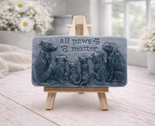 Load image into Gallery viewer, A rectangular handmade vegan soap bar gift, featuring a detailed relief carving of several dogs and a cat sitting together, with the words "all paws matter" and two paw prints embossed at the top, displayed on a wooden easel. Made in Blackpool.