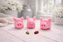 Load image into Gallery viewer, A set of three handmade vegan soaps sculpted into cute pigs with round snouts and floppy ears, displayed with a small decorative bee and ladybird on a white wooden surface.