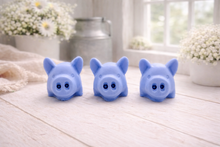 Load image into Gallery viewer, A set of three handmade vegan soaps sculpted into cute pigs with round snouts and floppy ears, displayed with a small decorative bee and ladybird on a white wooden surface.