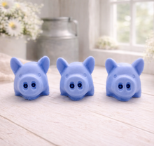 Load image into Gallery viewer, A set of three handmade vegan soaps sculpted into cute pigs with round snouts and floppy ears, displayed with a small decorative bee and ladybird on a white wooden surface.