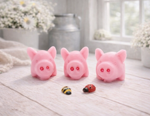 Load image into Gallery viewer, A set of three handmade vegan soaps sculpted into cute pigs with round snouts and floppy ears, displayed with a small decorative bee and ladybird on a white wooden surface.
