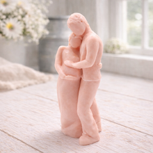 Load image into Gallery viewer, A 3D handmade vegan soap in a warm cream tone, sculpted into a standing figure of a pregnant couple; the partner stands behind the expectant mother, tenderly cradling her baby bump, displayed on a light wooden surface in a bright farmhouse setting.