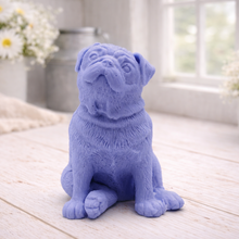 Load image into Gallery viewer, A detailed handmade vegan soap sculpted in the shape of a sitting pug dog with characteristic facial wrinkles and a tilted head, in a charcoal-grey tone, displayed on a light wooden surface.