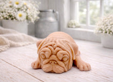 Load image into Gallery viewer, A detailed handmade vegan soap gift, sculpted in the shape of a pug dog lying flat on its stomach in a sleeping position, showing realistic skin folds and fur texture, displayed on a light wooden surface. Handmade in Blackpool