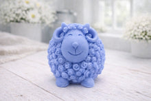 Load image into Gallery viewer, A highly detailed handmade vegan soap sculpted in the shape of a sturdy ram with a thick coat of tight, curly wool and large, elegant curved horns, displayed on a light wooden surface in a bright farmhouse setting.