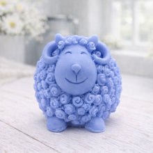 Load image into Gallery viewer, A highly detailed handmade vegan soap sculpted in the shape of a sturdy ram with a thick coat of tight, curly wool and large, elegant curved horns, displayed on a light wooden surface in a bright farmhouse setting.