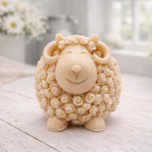 Load image into Gallery viewer, A highly detailed handmade vegan soap sculpted in the shape of a sturdy ram with a thick coat of tight, curly wool and large, elegant curved horns, displayed on a light wooden surface in a bright farmhouse setting.