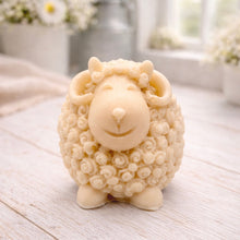 Load image into Gallery viewer, A highly detailed handmade vegan soap sculpted in the shape of a sturdy ram with a thick coat of tight, curly wool and large, elegant curved horns, displayed on a light wooden surface in a bright farmhouse setting.