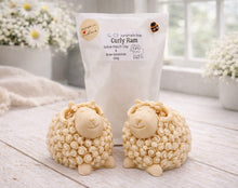 Load image into Gallery viewer, A highly detailed handmade vegan soap sculpted in the shape of a sturdy ram with a thick coat of tight, curly wool and large, elegant curved horns, displayed on a light wooden surface in a bright farmhouse setting.