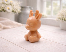 Load image into Gallery viewer, A 3D handmade vegan soap crafted into a cute, sitting baby reindeer with small antlers, rounded features, and a sweet expression, set against a bright farmhouse window.