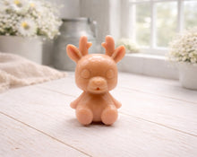 Load image into Gallery viewer, A 3D handmade vegan soap crafted into a cute, sitting baby reindeer with small antlers, rounded features, and a sweet expression, set against a bright farmhouse window.