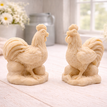 Load image into Gallery viewer, Two handmade vegan soaps sculpted in the shape of proud roosters (cockerels) with detailed feathers, combs, and curved tail feathers, standing on a rustic base, in a natural colour. Gift boxed
