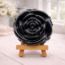Load image into Gallery viewer, A handmade vegan soap, intricately sculpted in the shape of a large, blooming rose flower with layered petals, displayed on a small wooden easel against a bright win