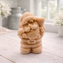 Load image into Gallery viewer, A highly detailed 3D handmade vegan soap featuring a Father Christmas carrying a large sack of gifts over his shoulder and holding a bell, featuring an intricate curly beard and fur-trimmed suit, set against a festive holiday background.