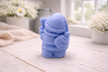 Load image into Gallery viewer, A highly detailed 3D handmade vegan soap featuring a Father Christmas carrying a large sack of gifts over his shoulder and holding a bell, featuring an intricate curly beard and fur-trimmed suit, set against a festive holiday background.