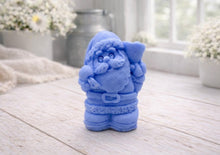 Load image into Gallery viewer, A highly detailed 3D handmade vegan soap featuring a Father Christmas carrying a large sack of gifts over his shoulder and holding a bell, featuring an intricate curly beard and fur-trimmed suit, set against a festive holiday background.