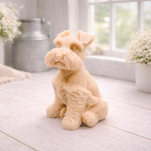 Load image into Gallery viewer, A detailed handmade vegan soap sculpted in the shape of a sitting Schnauzer dog with characteristic fluffy eyebrows and beard, in a natural colour, set against a bright window and white flowers. By soap Simple creations