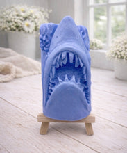 Load image into Gallery viewer, A 3D handmade vegan soap sculpted into a realistic great white shark head with its jaws wide open to reveal multiple rows of sharp teeth, displayed on a miniature wooden easel in a bright farmhouse setting.
