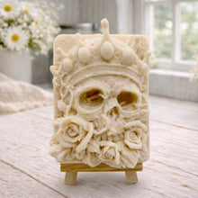 Load image into Gallery viewer, handmade vegan soap gift featuring a detailed relief of a skull wearing a crown, surrounded by a border of roses, displayed on a small wooden easel.