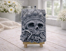 Load image into Gallery viewer, handmade vegan soap gift featuring a detailed relief of a skull wearing a crown, surrounded by a border of roses, displayed on a small wooden easel.