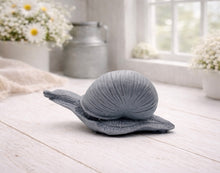 Load image into Gallery viewer, A highly detailed handmade vegan soap gift, sculpted in the shape of a realistic snail with a prominent spiralled shell and a textured, leathery body, displayed on a light wooden surface. Handmade in Blackpool.