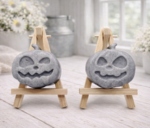 Load image into Gallery viewer, A collection of six handmade vegan Halloween soaps in a mottled grey and black charcoal finish, featuring a smiling bat, three different carved pumpkins (one wearing a witch's hat), a ghost, and a skull, arranged on and around a small wooden easel.