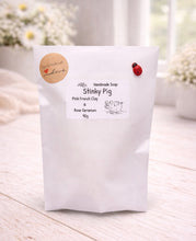 Load image into Gallery viewer, Handmade soap packaging with 'Stinky Pig' branding on a light wooden surface.