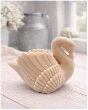 Load image into Gallery viewer, handmade vegan soap, sculpted into the shape of a graceful swan with detailed feathering on its wings and a curved neck, displayed on a light wooden surface in a bright farmhouse setting.