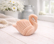 Load image into Gallery viewer, A 3D handmade vegan soap, sculpted into the shape of a graceful swan with detailed feathering on its wings and a curved neck, displayed on a light wooden surface in a bright farmhouse setting.