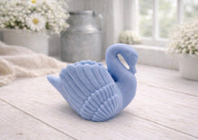Load image into Gallery viewer, A 3D handmade vegan soap, sculpted into the shape of a graceful swan with detailed feathering on its wings and a curved neck, displayed on a light wooden surface in a bright farmhouse setting.