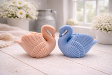 Load image into Gallery viewer, A 3D handmade vegan soap, sculpted into the shape of a graceful swan with detailed feathering on its wings and a curved neck, displayed on a light wooden surface in a bright farmhouse setting.