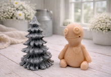 Load image into Gallery viewer, A handmade vegan soap gift set featuring a cream-coloured voodoo doll soap with stitched details and a grey tiered Christmas tree soap, presented in a black gift box tied with a red raffia ribbon and a small ladybird embellishment.