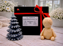 Load image into Gallery viewer, A handmade vegan soap gift set featuring a cream-coloured voodoo doll soap with stitched details and a grey tiered Christmas tree soap, presented in a black gift box tied with a red raffia ribbon and a small ladybird embellishment.