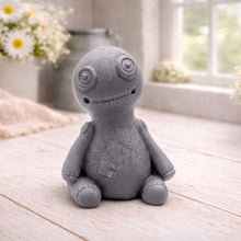 Load image into Gallery viewer, A handmade vegan soap gift in the shape of a stitched voodoo doll with button eyes and a small patch on its chest, sitting on a light wooden surface.