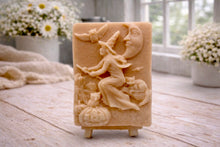 Load image into Gallery viewer, handmade vegan soap bar featuring a detailed relief carving of a witch flying on a broomstick past a crescent moon, owls, and pumpkins.