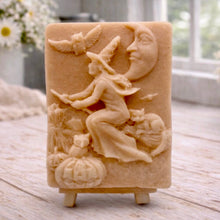Load image into Gallery viewer, handmade vegan soap bar featuring a detailed relief carving of a witch flying on a broomstick past a crescent moon, owls, and pumpkins.